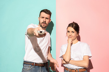 Image showing Couple bored watching tv with a the hand holding the remote control standing at studio