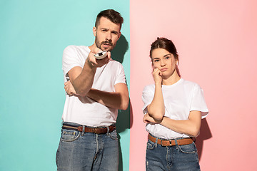 Image showing Couple bored watching tv with a the hand holding the remote control standing at studio