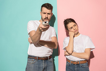 Image showing Couple bored watching tv with a the hand holding the remote control standing at studio