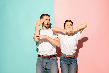 Image showing Closeup portrait of young couple, man, woman. TV fan concept on pink and blue background. Emotion contrasts