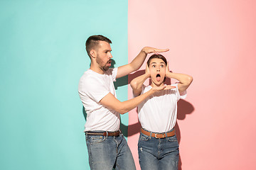 Image showing Closeup portrait of young couple, man, woman. TV fan concept on pink and blue background. Emotion contrasts