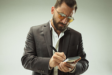 Image showing Male beauty concept. Portrait of a fashionable young man with stylish haircut wearing trendy suit posing over gray background.