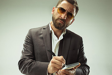 Image showing Male beauty concept. Portrait of a fashionable young man with stylish haircut wearing trendy suit posing over gray background.