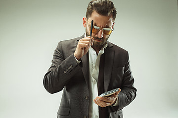 Image showing Male beauty concept. Portrait of a fashionable young man with stylish haircut wearing trendy suit posing over gray background.