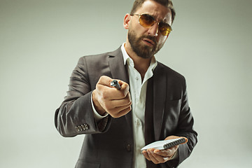 Image showing Male beauty concept. Portrait of a fashionable young man with stylish haircut wearing trendy suit posing over gray background.