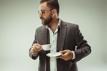 Image showing Male beauty concept. Portrait of a fashionable young man with stylish haircut wearing trendy suit posing over gray background.