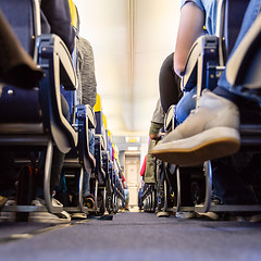 Image showing Low agle view of passenegers commercial airplane aisle with passenegers sitting on their seats while flying