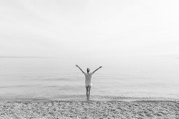 Image showing Happy Carefree Woman Enjoying Sunset Walk on White Pabbled Beach.