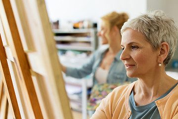 Image showing senior woman drawing on easel at art school studio