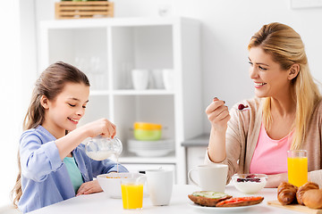 Image showing happy mother and daughter having breakfast at home