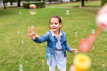 Image showing happy girl playing with soap bubbles at park