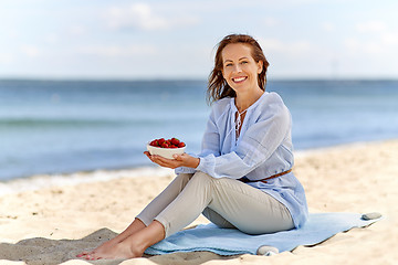 Image showing woman holding bowl with strawberries on beach