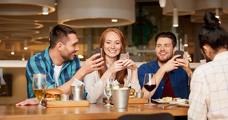 Image showing happy friends with smartphones at restaurant