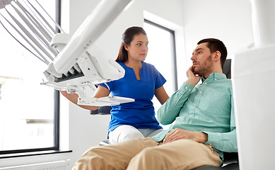 Image showing man with toothache and dentist at dental clinic