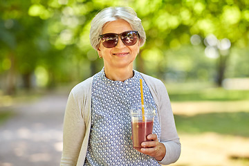 Image showing senior woman drinking takeaway shake at park