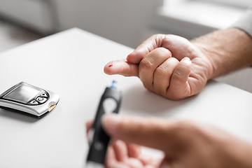 Image showing senior man with glucometer checking blood sugar