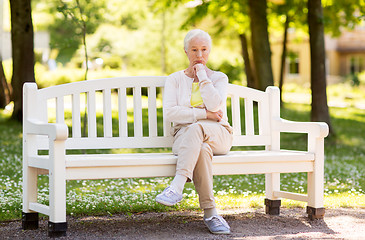 Image showing sad senior woman sitting on bench at summer park