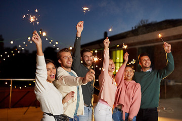 Image showing happy friends with sparklers at rooftop party