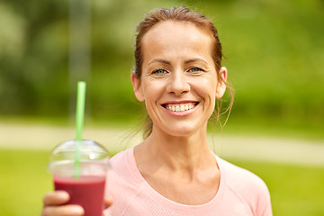 Image showing woman drinking smoothie after exercising in park