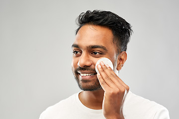 Image showing smiling indian man cleaning face with cotton pad