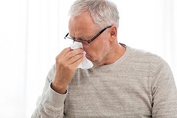 Image showing sick senior man with paper wipe blowing his nose