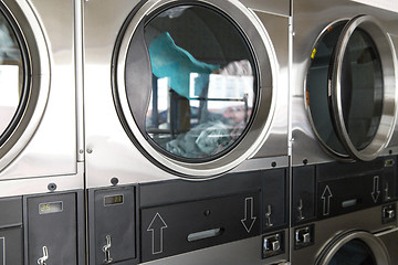 Image showing washing machines with clothes inside at laundromat