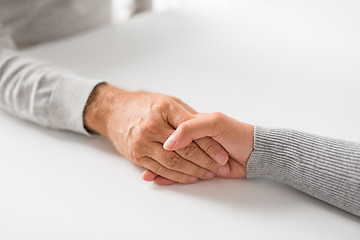 Image showing close up of young woman holding senior man hands