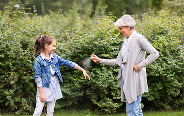 Image showing grandma and granddaughter with insect repellent