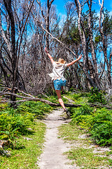 Image showing Girl outdoors jumping over tree fallen across track