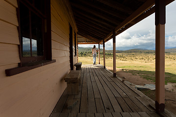 Image showing Woman standing on verandah of rural timber homestead in snowy high plains