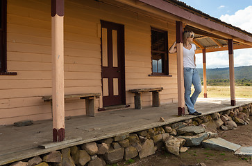 Image showing Happy relaxed female on verandah of old timber home in the rural countryside