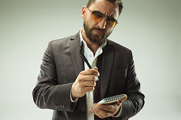 Image showing Male beauty concept. Portrait of a fashionable young man with stylish haircut wearing trendy suit posing over gray background.