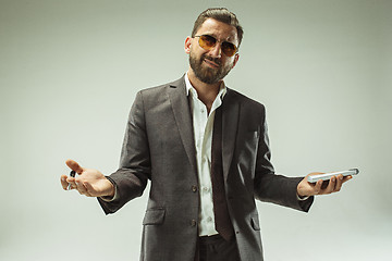 Image showing Male beauty concept. Portrait of a fashionable young man with stylish haircut wearing trendy suit posing over gray background.