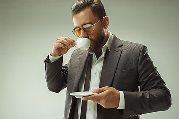 Image showing Male beauty concept. Portrait of a fashionable young man with stylish haircut wearing trendy suit posing over gray background.