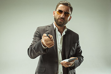 Image showing Male beauty concept. Portrait of a fashionable young man with stylish haircut wearing trendy suit posing over gray background.