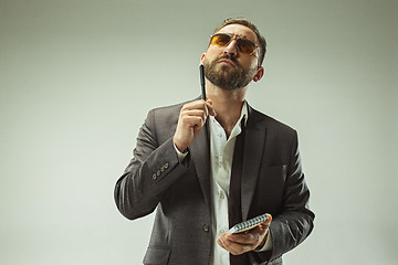 Image showing Male beauty concept. Portrait of a fashionable young man with stylish haircut wearing trendy suit posing over gray background.