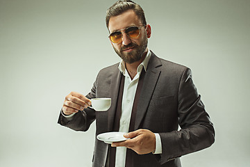 Image showing Male beauty concept. Portrait of a fashionable young man with stylish haircut wearing trendy suit posing over gray background.