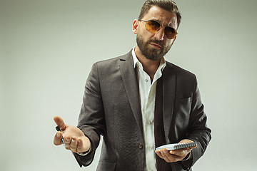 Image showing Male beauty concept. Portrait of a fashionable young man with stylish haircut wearing trendy suit posing over gray background.