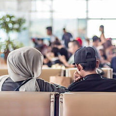 Image showing Modern muslim islamic asian couple sitting and waiting for flight departure at international airport terminal