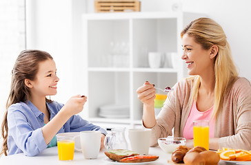 Image showing happy mother and daughter having breakfast at home