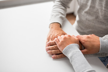 Image showing close up of young woman holding senior man hands