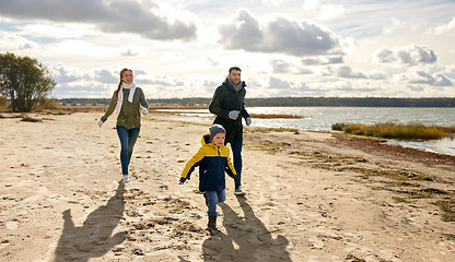 Image showing happy family running along autumn beach