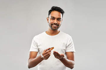 Image showing indian man applying grooming oil to his hand