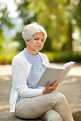 Image showing senior woman reading book at summer park