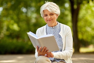 Image showing senior woman reading book at summer park