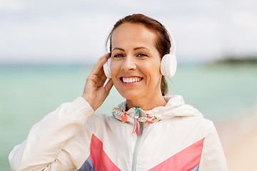 Image showing woman with headphones listening to music on beach