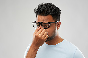 Image showing tired indian man in glasses rubbing nose bridge