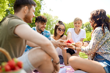 Image showing happy friends sharing watermelon at summer picnic