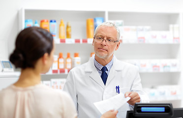 Image showing senior apothecary with prescription at pharmacy