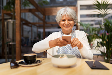 Image showing senior woman photographing food at street cafe